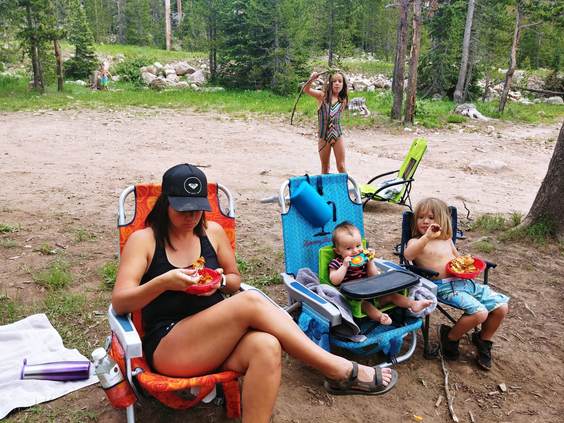 Leah and the kids eating lunch in camp chairs in the forest