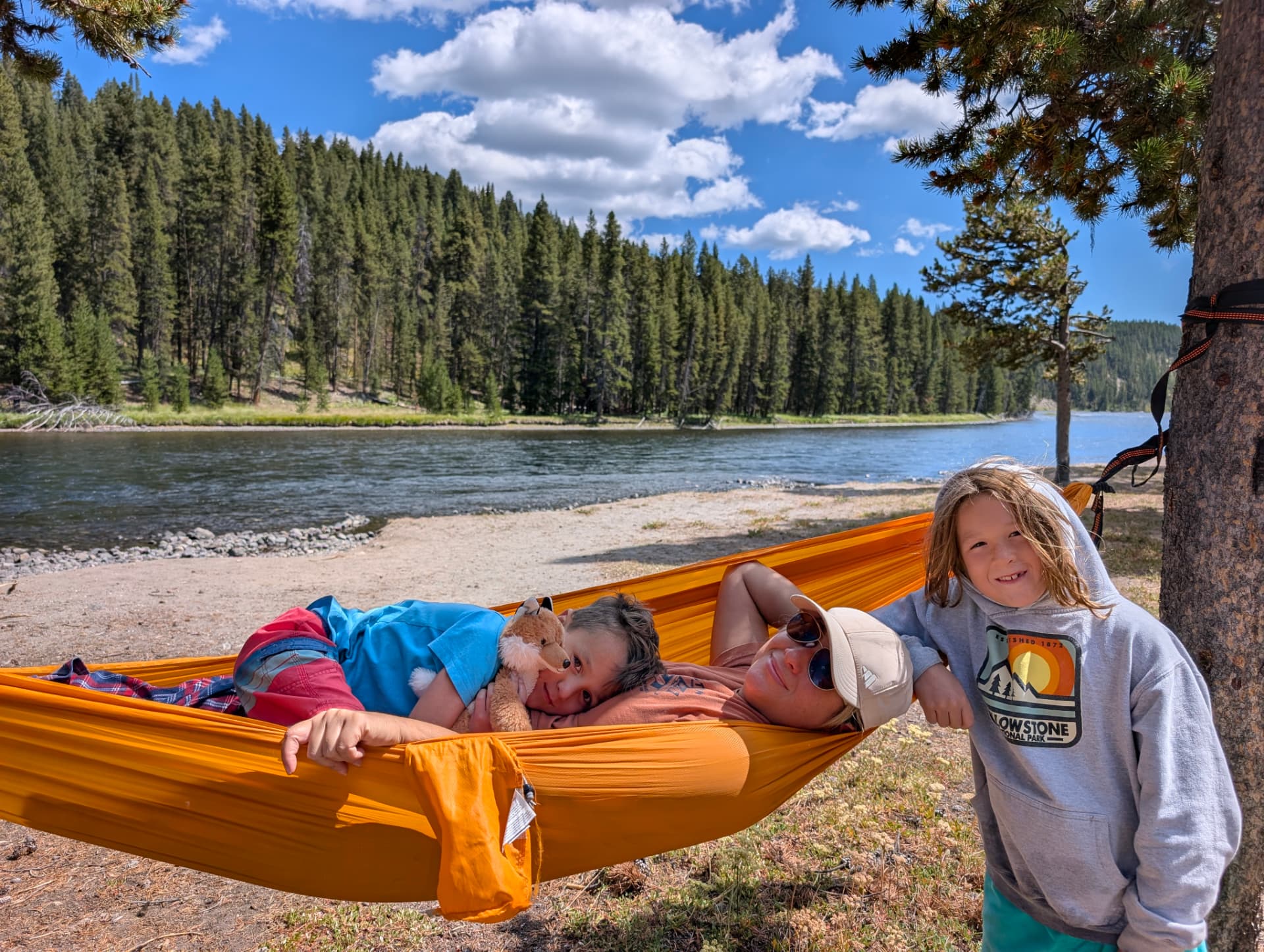Leah resting in a hammock with two of her kids beside the Yellowstone River